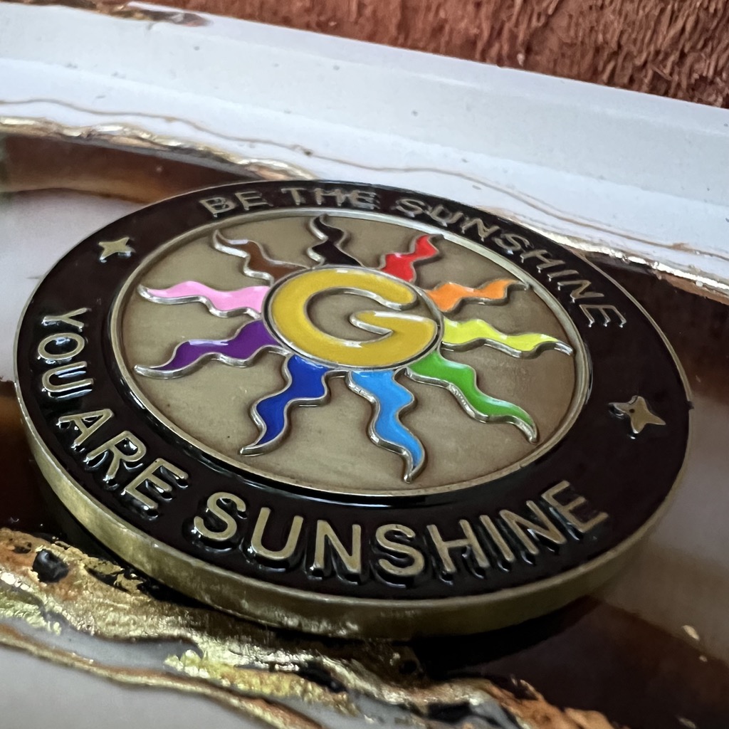 Close up of the B Side of the wizard coin with its enamel rainbow sun rays catching the light.